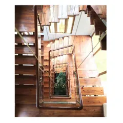 A view looking down the timber and steel staircase of the 'Aangan' house. This project was about creating a warm, biophilic space, and this central feature connects the floors while drawing the eye towards the greenery below.