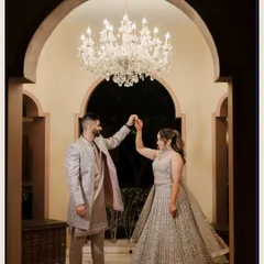 A romantic moment under a grand chandelier, as the groom twirls his bride during their engagement or Sangeet ceremony.
