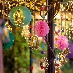 A close-up of colorful hanging decorations for a festive event. I layered paper lanterns, honeycombs, and fairy lights to create a rich, textured, and vibrant look.