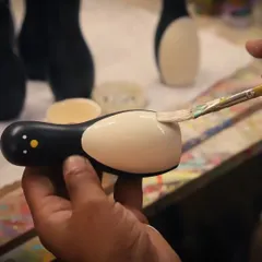 The final details are always painted by hand. This close-up shows an artisan carefully applying natural dye to a penguin toy, a testament to the skill and patience that goes into every single piece we create. This is what makes each Channapatna wooden toy unique.