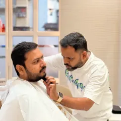 Our client looks on as we meticulously shape his beard. This is a moment of focus and precision, core to our beard grooming and styling services.