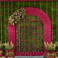 For this Ganpati celebration, I designed a vibrant floral arch using pink blossoms against a lush green backdrop of banana leaves. The hanging strings of jasmine and roses add a delicate, traditional touch.