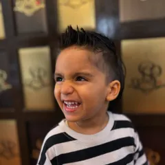 Even our youngest clients leave with the coolest cuts. This little guy is rocking a stylish mohawk with a sharp fade, and his happy expression says it all.