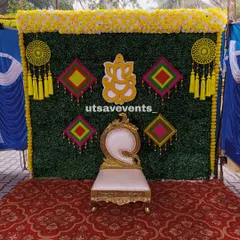 A colorful Mehendi backdrop featuring a grass wall decorated with a Ganesha cutout and vibrant hanging tassels. This design is perfect for a lively celebration.