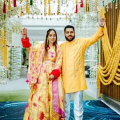 The couple makes a grand entrance at their Haldi ceremony, waving to guests under a beautiful floral decor.