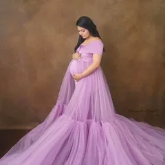 A serene studio portrait in a light lavender gown with an expansive, flowing train. This style creates a soft and dreamy look, perfect for timeless maternity pictures.