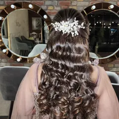 A stunning half-up, half-down hairstyle with voluminous curls. The look is finished with a delicate, sparkling hair accessory, making it perfect for an engagement or reception.