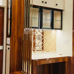 This crockery unit was designed to integrate seamlessly with the traditional decor of the living room. It features rich wood, mirrored accents with ethnic motifs, and glass shutters, blending modern storage needs with classic style.