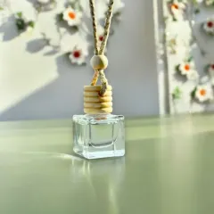A clean product shot of the hanging car freshener. The simple design, featuring a glass bottle and a wooden diffuser cap, is both functional and aesthetically pleasing.