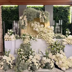 For clients who dream of a classic, all-white wedding, we design ethereal wonderlands like this. We layered voluminous clouds of baby's breath with white roses and hydrangeas against a green wall to create a breathtaking floral installation that feels both timeless and magical.