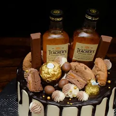 A close-up of the delicious toppings on the loaded whiskey cake. You can see the mix of Teacher's whiskey miniatures, Ferrero Rocher, Hershey's Kisses, and pieces of chocolate bars.