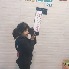 The proud creator with her finished, working periscope. We don't just help them complete the project; we help them understand it so they can present it confidently.
