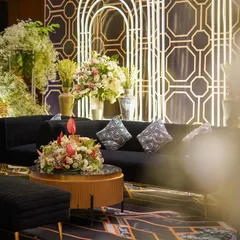 An angled view of the stylish black and gold lounge seating. The combination of modern furniture, geometric patterns, and soft floral arrangements creates a perfect balance of sophistication and warmth.