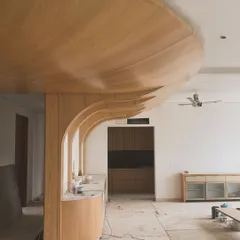 A work-in-progress shot showing the complex carpentry involved in creating a curved, wood-paneled ceiling and wall feature. This shows the skeleton before the final finishes are applied.
