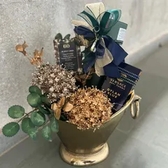 A sophisticated gift for a gentleman's 60th birthday. This champagne bucket holds premium spirits and is decorated with dried florals and masculine accents in a deep green and gold color palette.
