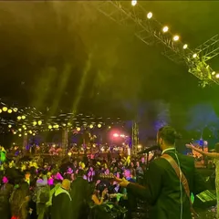A view from the back of the stage, looking out at the huge crowd. The combination of stage lights and festive decor makes for a truly special night.