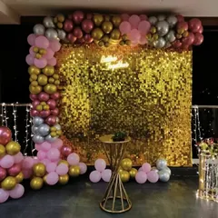 A glamorous party backdrop perfect for a bridal shower or bachelorette party. This setup features a gold sequin wall framed by a stunning balloon arch in shades of pink, gold, and silver.