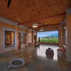 The welcome lounge at Waghoba Ecolodge, featuring a vaulted roof made with local pottery tiles and walls of stabilized adobe. The open design frames a panoramic view of the distant hills, immediately immersing guests in the natural setting.