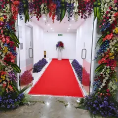 This view shows how a floral arch and red carpet can transform a simple hallway into a grand entrance for an office opening. The arrangement guides guests into the main event space.