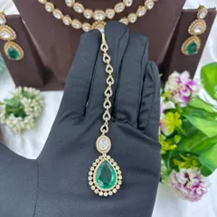 The maang tikka for the emerald layered necklace set, held to show its detail.
