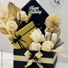 A chic and modern birthday hamper with a black, gold, and cream color scheme. The gift box is filled with elegantly wrapped presents and decorated with dried flowers, perfect for a sophisticated celebration.