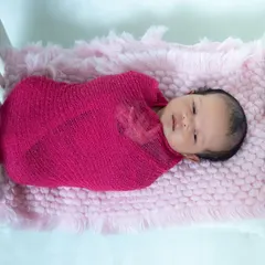 Pretty in pink. We use soft, stretchy wraps to keep newborns feeling secure and snug during their photoshoot, resulting in these adorable, peaceful portraits.