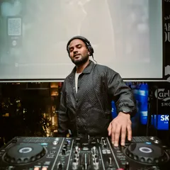 A moment of calm before the crowd arrives. This shot captures me at my console, with the city lights in the background, ready to start the night's musical journey.