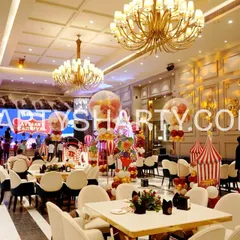 A wide-angle view of a carnival-themed party, showing the complete venue transformation with themed centerpieces, backdrops, and guest seating.