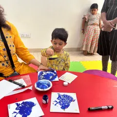 A young artist carefully works on a peacock feather stencil print during our Janmashtami celebration. We combine cultural themes with fun, accessible art projects for all our students.