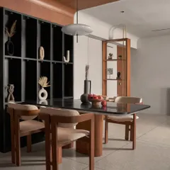 A wide shot of the dining area, showing its relationship to the living space. The black open display cabinet provides storage while maintaining the minimalist aesthetic, showcasing curated decor pieces.