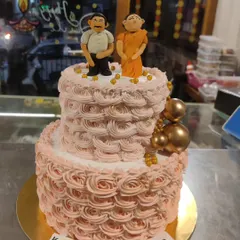 A two-tier anniversary cake for "Mummy & Baba." This cake features delicate pink rosette piping and custom fondant figurines of the couple.
