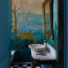 Powder bathrooms are my canvas for playful storytelling. Here, a hand-painted mural of a cheetah brings a touch of the wild indoors, complemented by a classic checkerboard floor and a gilded mirror, creating a whimsical yet elegant escape.