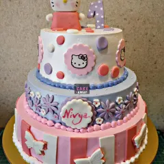 A three-tier Hello Kitty cake perfect for a first birthday. It combines different patterns, colors, and edible character plaques to create a beautiful and memorable design.