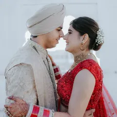 An intimate close-up where the couple shares a gentle, smiling moment. This shot highlights the intricate details of the bride's jewelry and the soft, natural light of the palace setting.