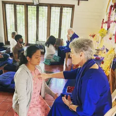 A devotee participating in a purification ceremony, receiving a blessing from Nayaswami Devi. This simple, powerful ritual is an opportunity to consciously let go of any obstacles and open the heart to God's grace.
