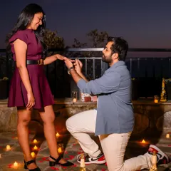He slips the ring on her finger in a beautifully arranged proposal setting, surrounded by the warm glow of countless candles.