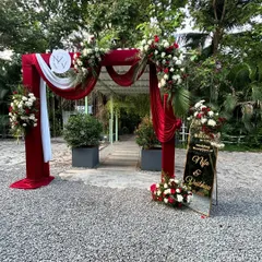 The grand entrance arch for a classic red and white themed wedding reception. The rich velvet drapes and abundant florals make a bold and elegant statement.