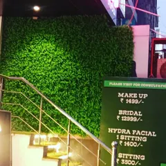 The same green wall at night, lit up to attract customers to this salon.