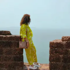 A woman in a vibrant yellow outfit looks out over the sea from the walls of a fort in Goa. This shot captures a moment of quiet contemplation and the feeling of wanderlust.