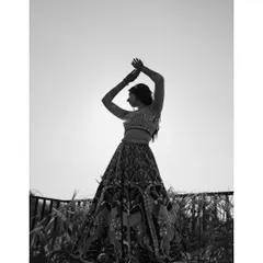 A bride's silhouette against the bright sky. This artistic, black and white shot focuses on her form and the intricate details of her lehenga, creating a timeless and elegant portrait.
