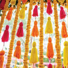 Details make the design. This backdrop features playful pink, yellow, and orange tassels hanging between elegant lines of marigold flowers, creating a perfect blend of charm and vibrancy.