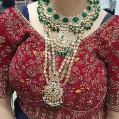 A bride looking absolutely regal in a layered green kundan and polki set, featuring a choker and a long multi-strand haar.