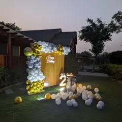 An angled view of the outdoor setup, showing the arrangement of the balloon arch and scattered balloons on the lawn.