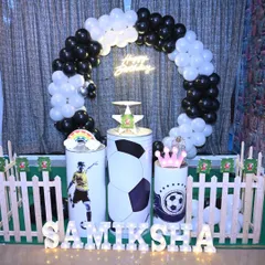 A football-themed birthday setup perfect for a young athlete. The decoration includes a black and white balloon ring, custom pedestals with football graphics, and a bright neon sign.