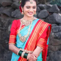 A classic bridal portrait featuring a beautiful bride in a traditional sky-blue and red Paithani saree. The focus is on her serene expression and the rich details of her attire.