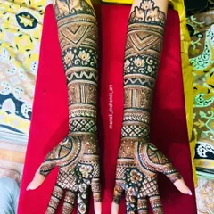 A beautiful bridal design featuring lotus and elephant motifs near the elbows. The arms are filled with a variety of traditional patterns, including checks, bands, and floral elements.
