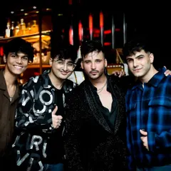 A group of friends celebrating in our custom party wear. The outfits range from a patterned shirt and jacket to a textured black coat, showing how we coordinate different styles for a night out.