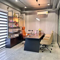 A private cabin in the corporate office, designed with a refined aesthetic. The space includes a modern desk, ergonomic chairs, and an open shelving unit for a look that is both professional and comfortable.