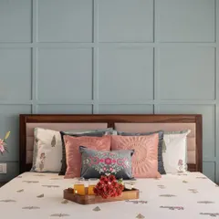 The master bed against a beautiful pastel blue paneled wall. We used simple, elegant reading lights and layered cushions to create a cozy and inviting look, proving that good design is all in the details.