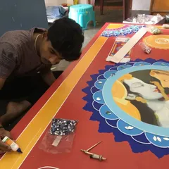 One of our artists carefully applies clay work and mirrors to a large mythological panel. This image shows the precision and steady hand required for our handmade Lippan art, ensuring every detail is perfect.